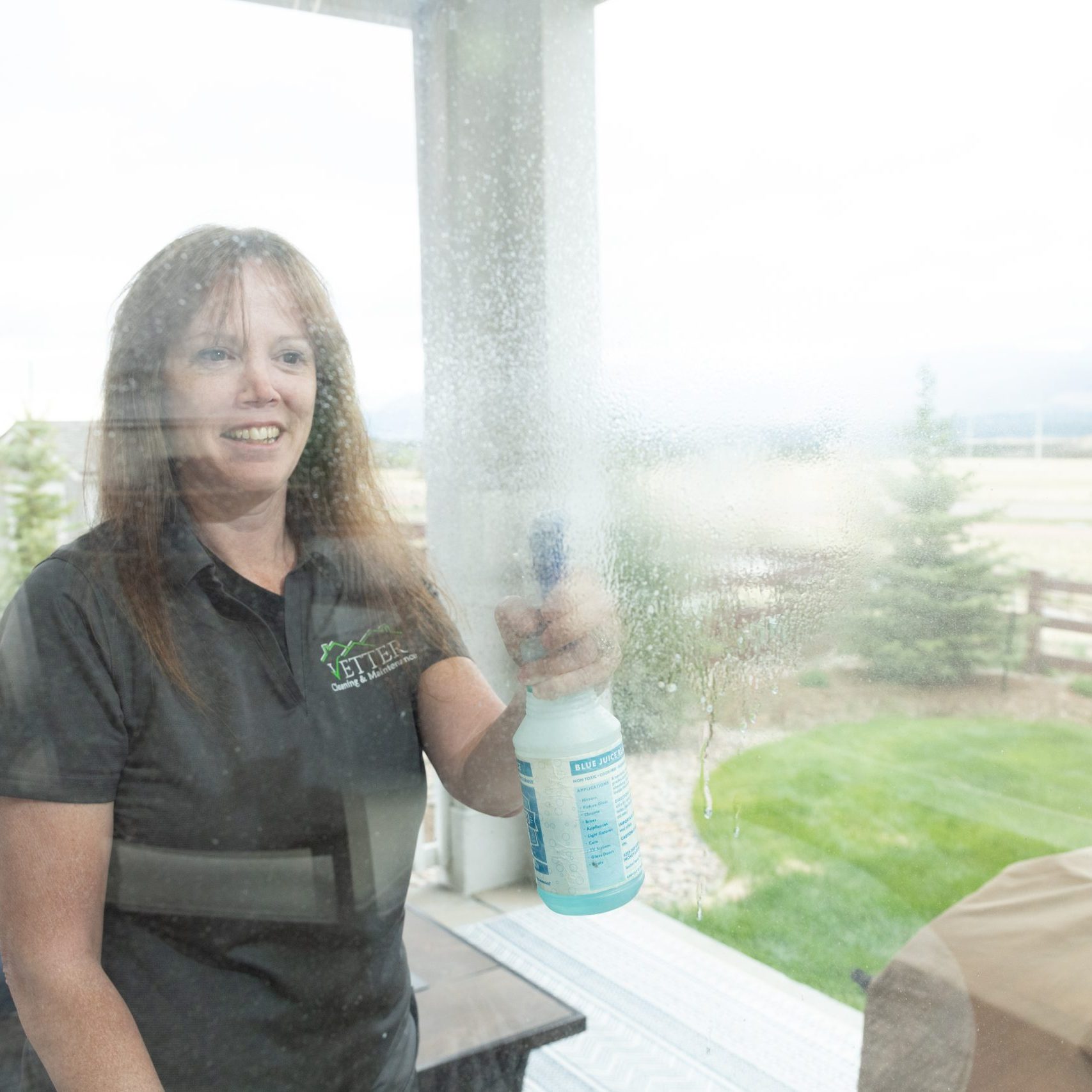 A maid from Vetter Cleaning of Colorado Springs washing interior windows as part of a deep cleaning service